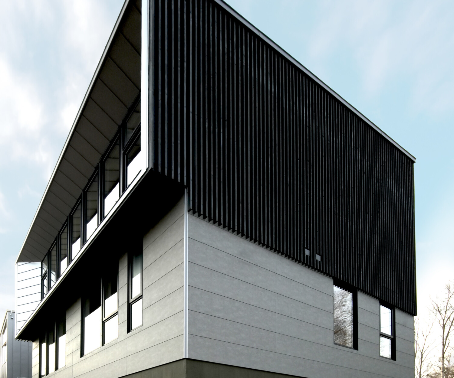 Yugen House architecture photo of a house in Niseko Japan with grey panels and black louvers and large glass portal window